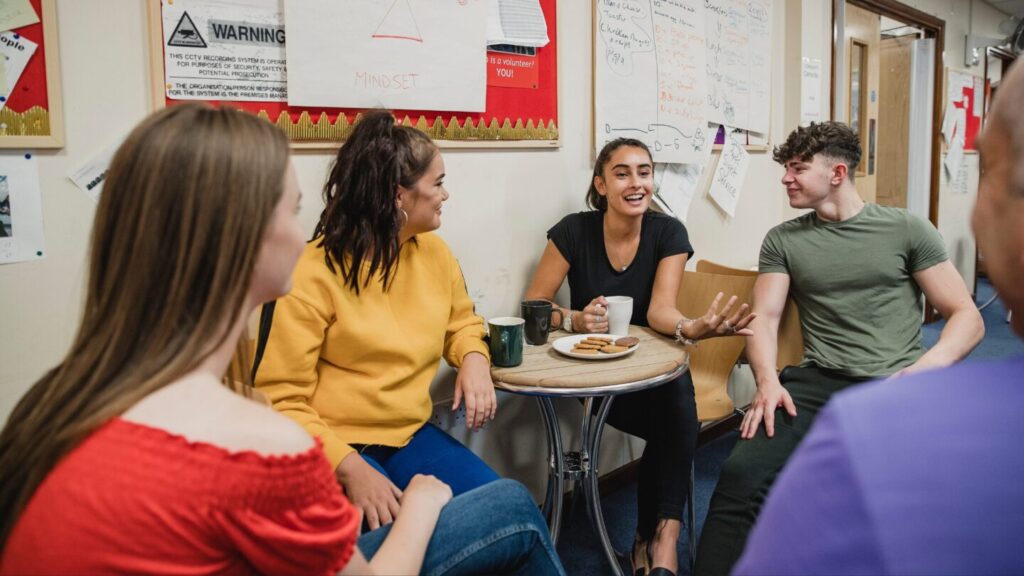 Group of young people sat around a table, talking.