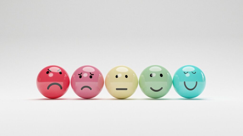 5 colourful balls in a line, each with a different emotion, from angry, sad, neutral, happy and very happy.