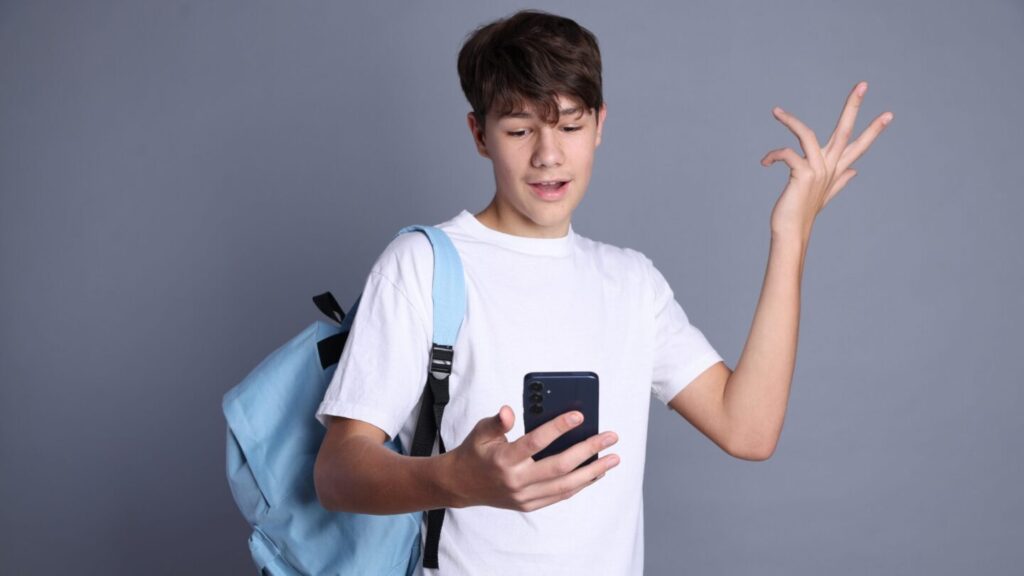 Teen boy looks confused at his phone screen