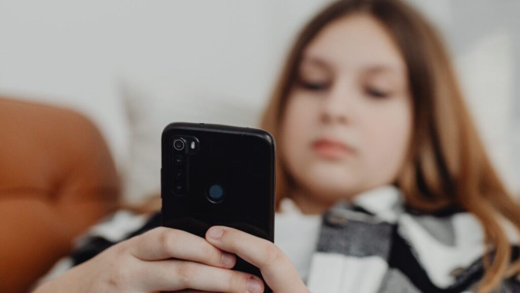 Teen girl sat on sofa using her mobile phone